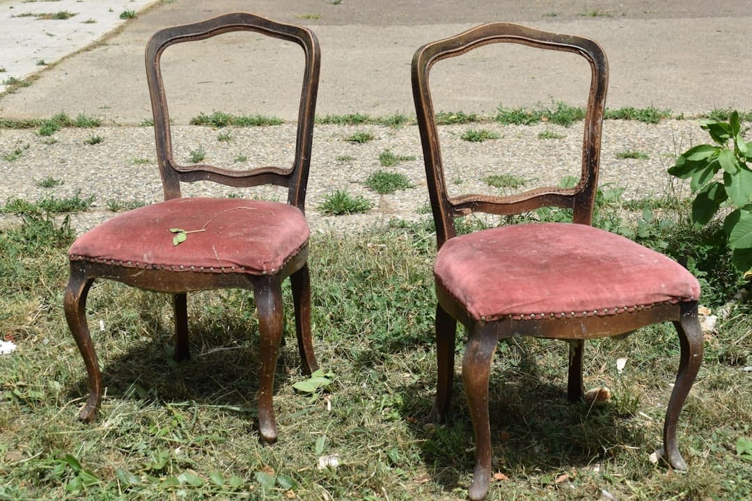 A pair of old wooden chairs with red upholstery before restoration